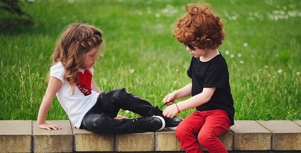 boy helps little girl tie shoelaces