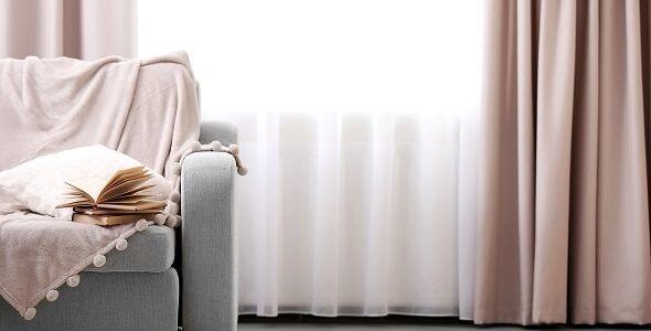 Opened book on comfortable sofa against window in the room